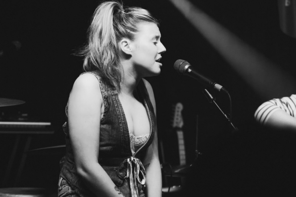 Robyn: singer singing into microphone on stage.